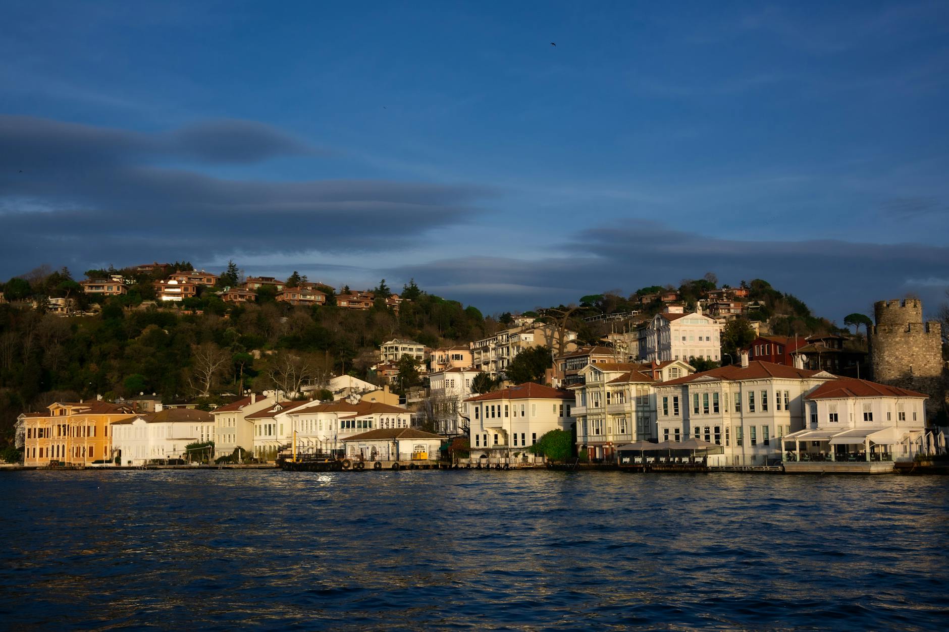 夕暮れ時に黄金色に照らされるイェニキョイの歴史的な木造邸宅群。